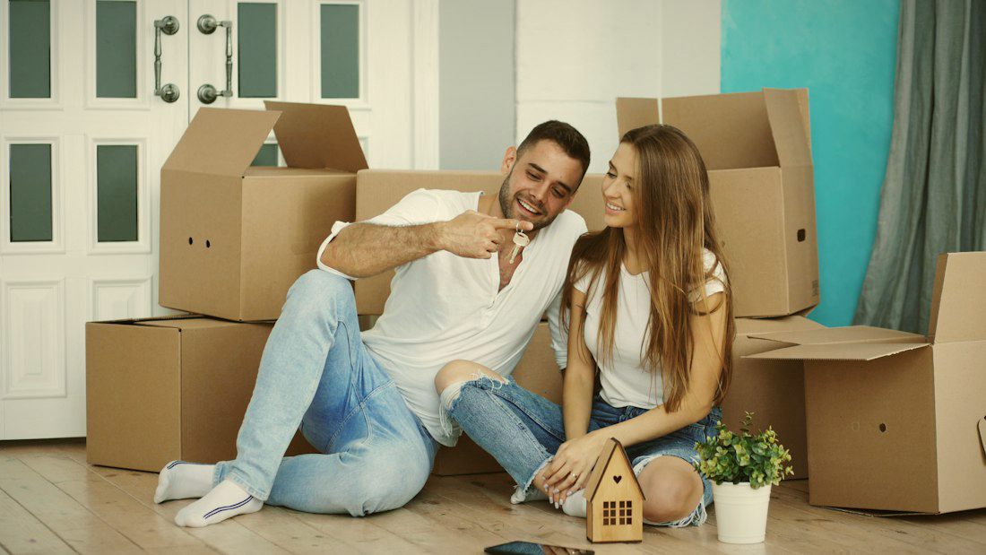 A happy couple sitting among moving boxes in their new home